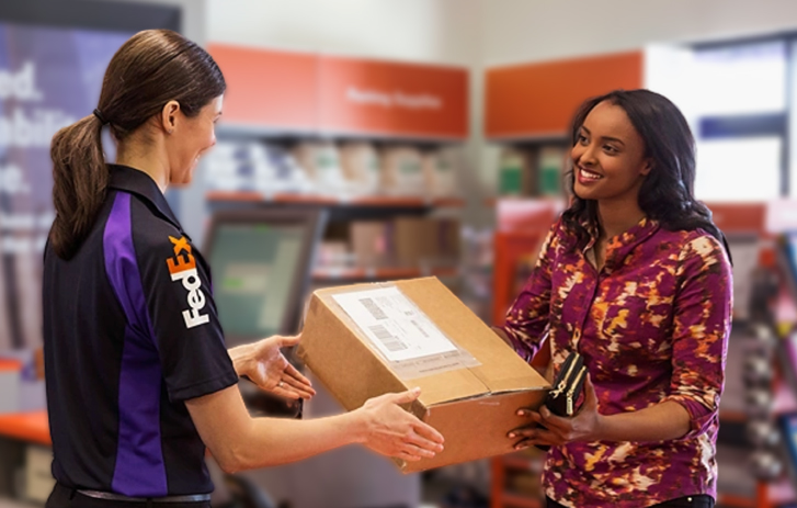 Uma funcionaria do FedEx entregando um pacote para uma mulher